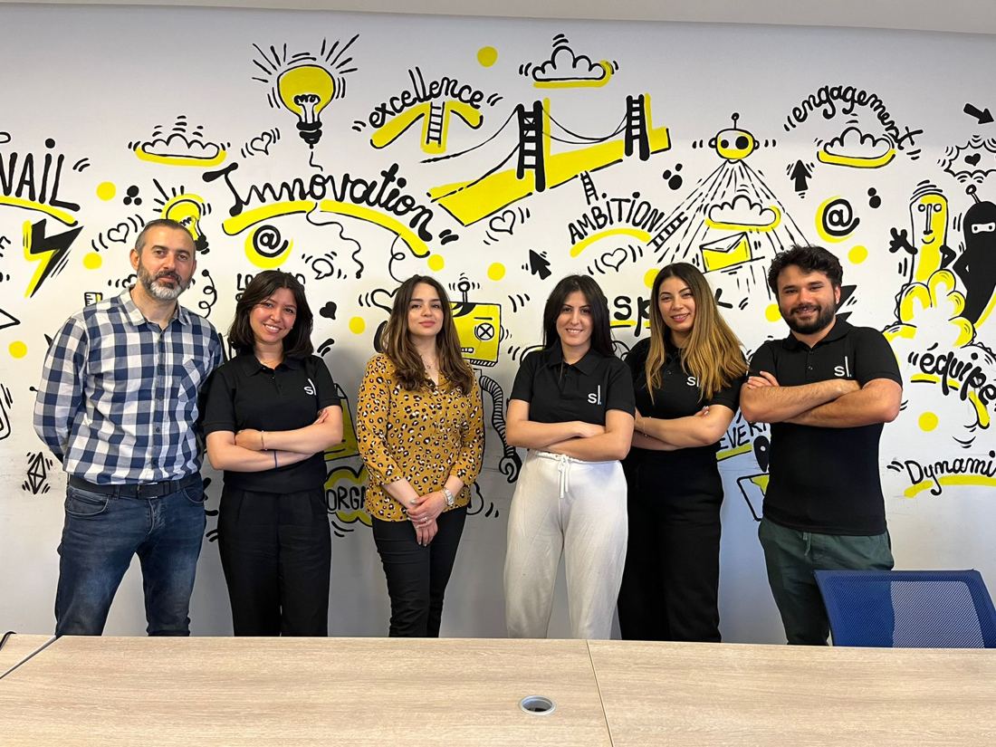 Six collaborateurs devant une fresque Innovation, Excellence, Engagement